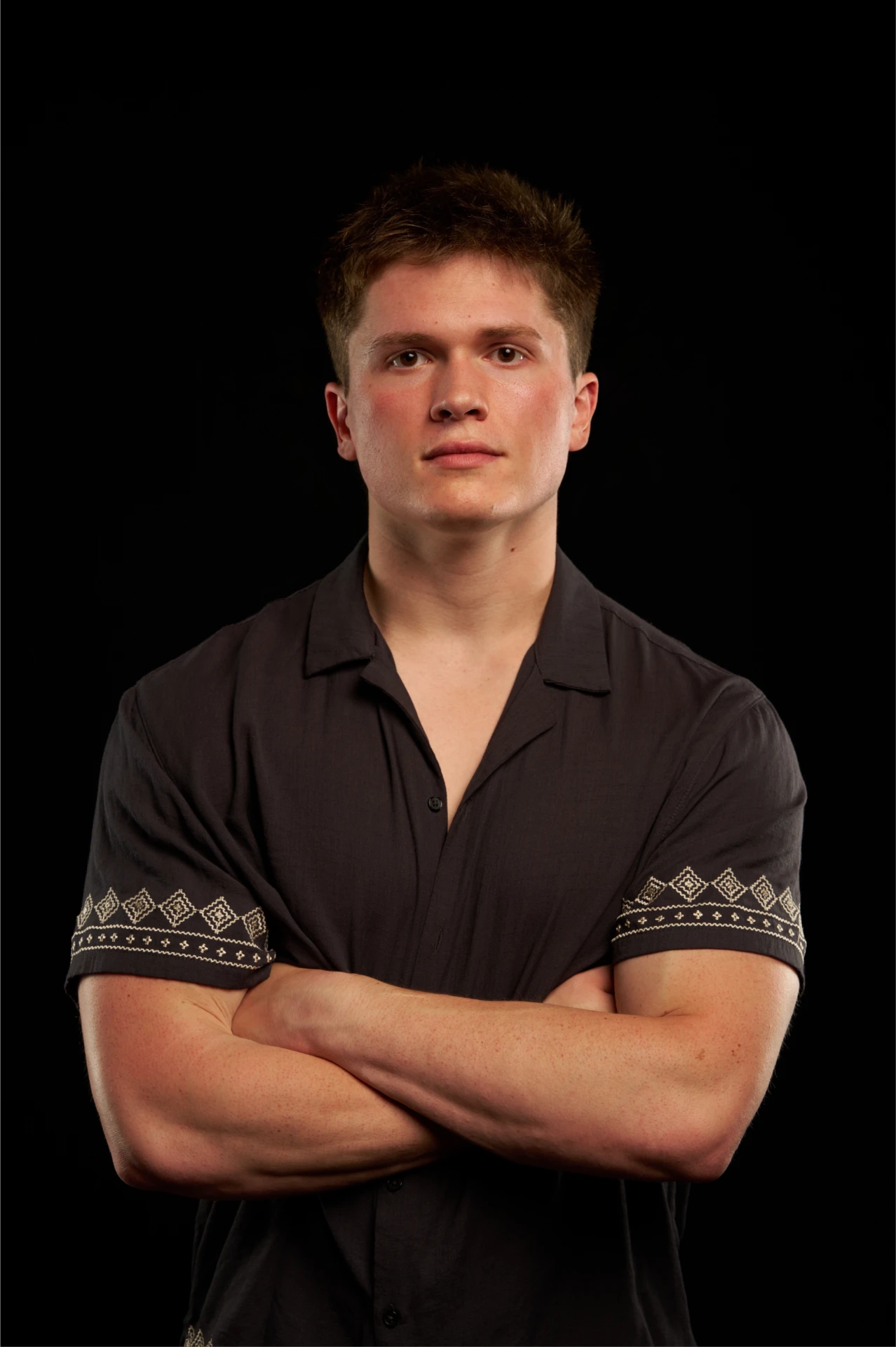 Jason Kushy studio portrait with arms crossed in a charcoal button-down shirt