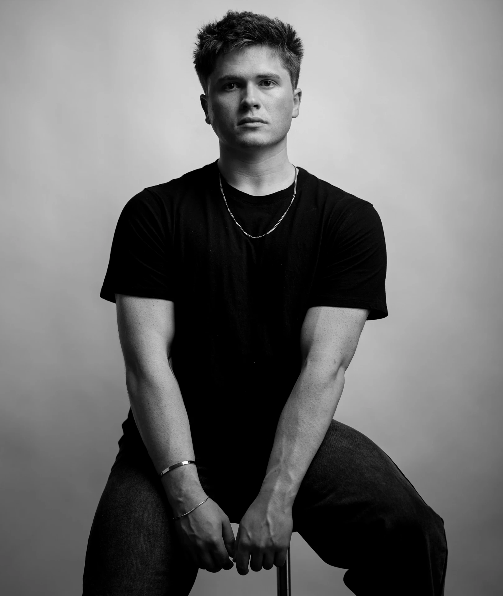 Black and white seated studio portrait of house music producer Jason Kushy