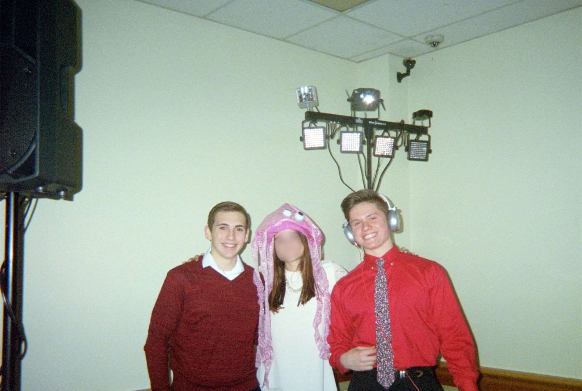 Young Jason Kushy wearing headphones at an early DJ event posing with friends