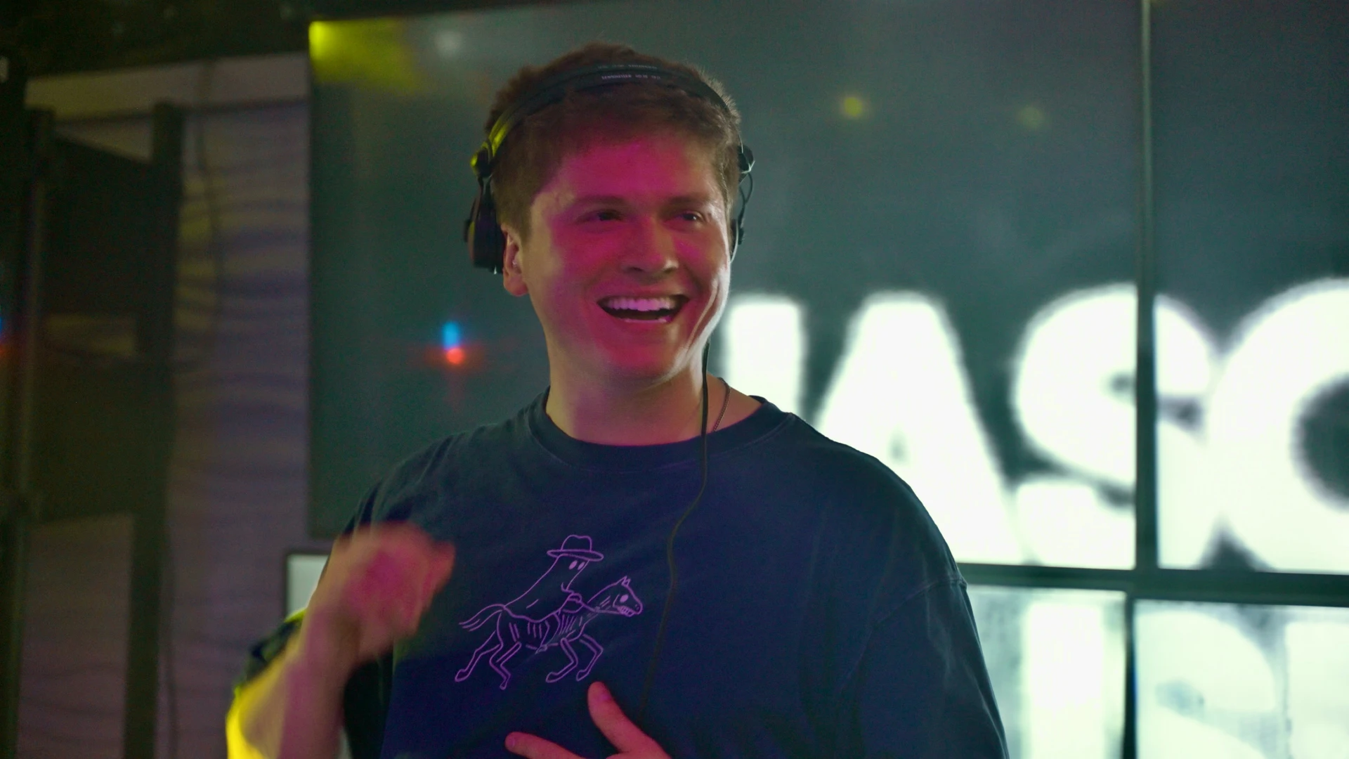 Jason Kushy live DJ performance under colorful laser lights on a dark club stage