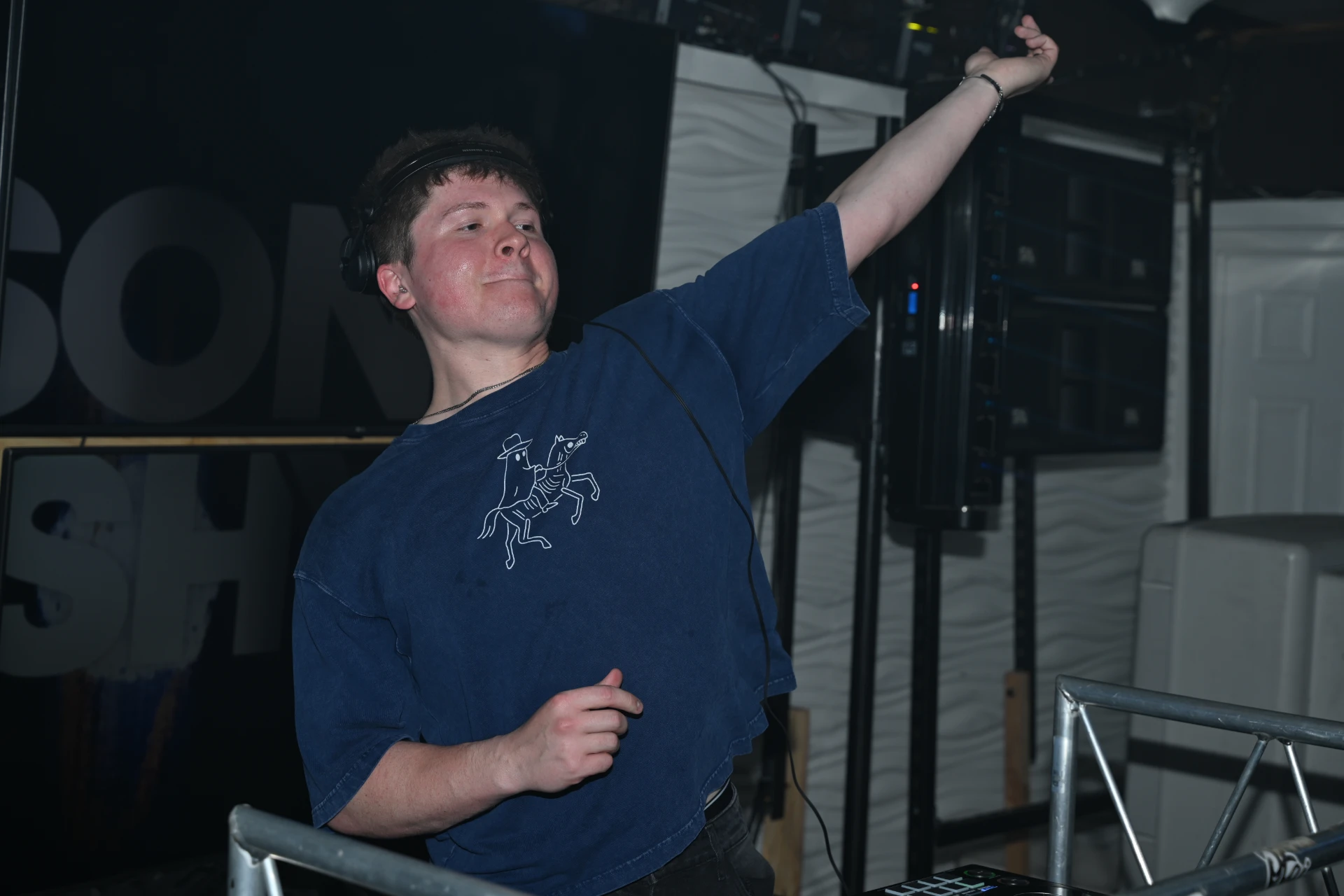 Jason Kushy live DJ set with KUSHY stage banner and speakers behind the booth
