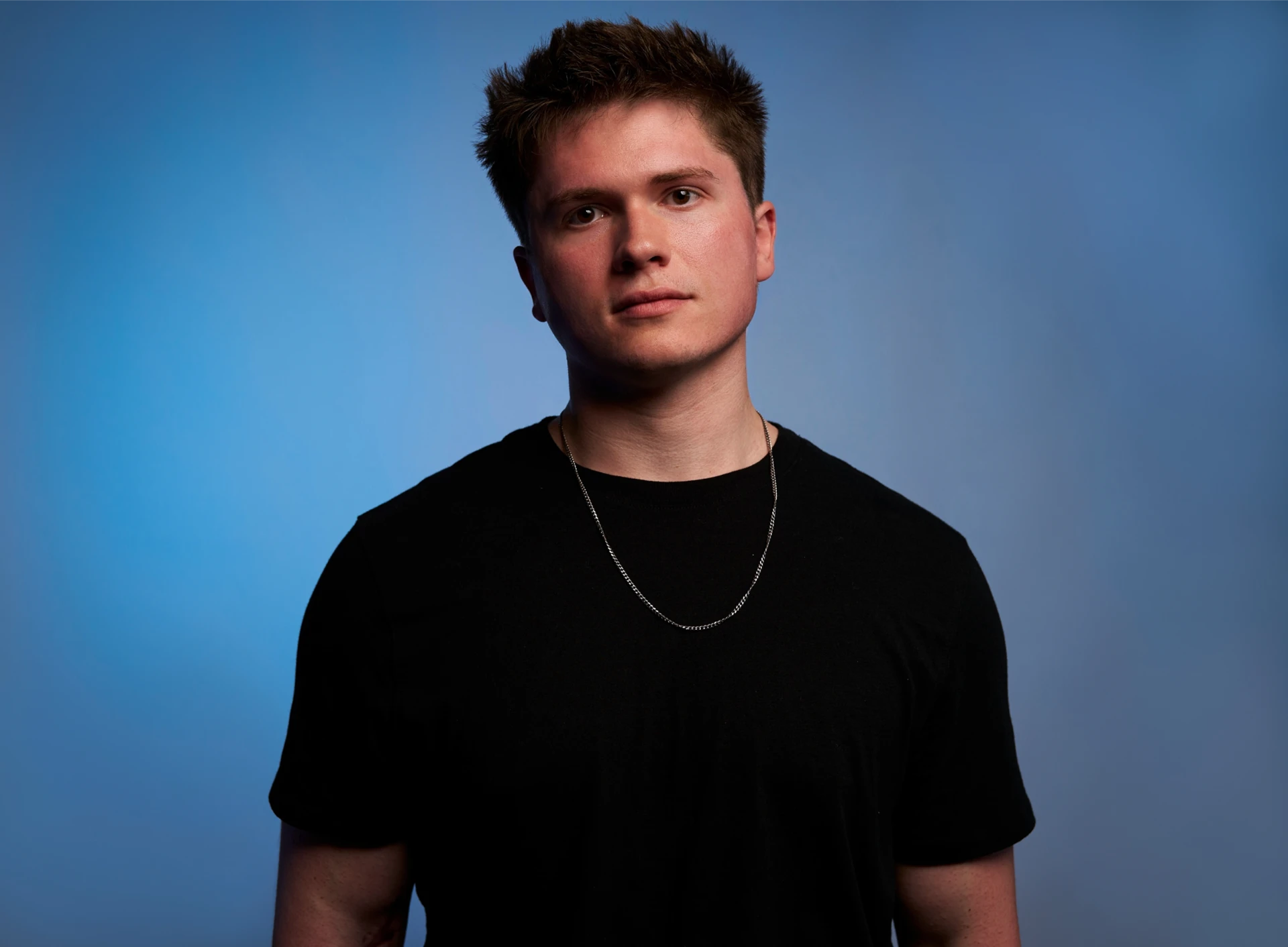 Studio headshot of American DJ and producer Jason Kushy against a blue backdrop
